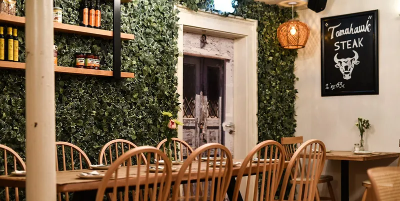Gastraum der Taverne mit Holzstühlen und Kreidetafel